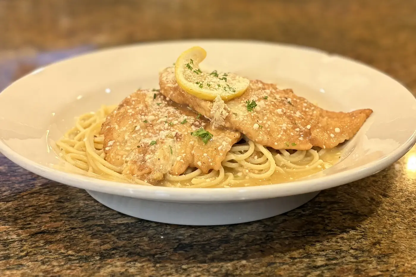 Chicken franchaise over pasta, topped with lemon and parsley