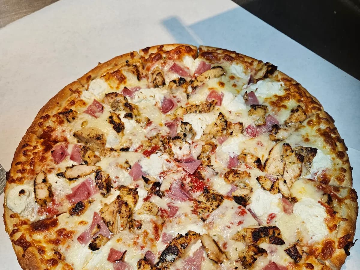 White pizza topped with grilled chicken, ham and ricotta