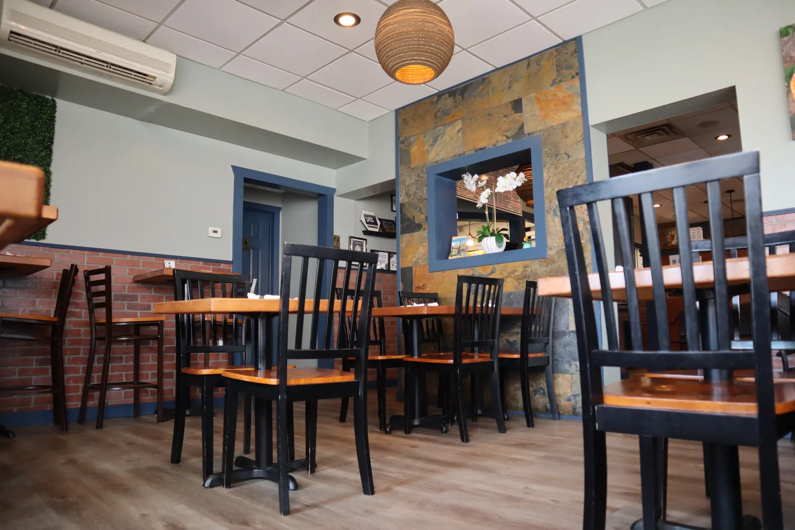 Dining area at Royal Xperience De'Maria with a stone accent wall and bistro tables