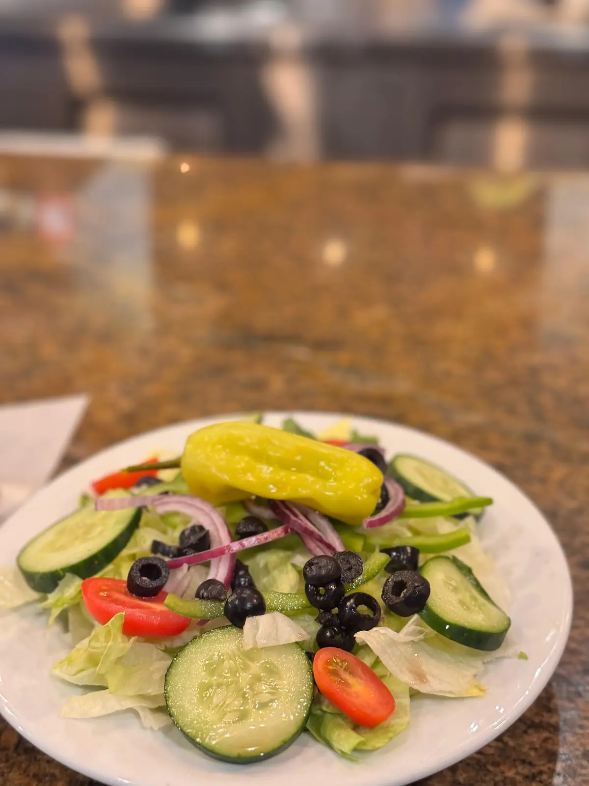 Garden salad with cucumbers, olives, tomatoes and a pepperoncini